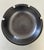 A classic Heath Ceramics ashtray in a rich matte gunmetal/charcoal glaze with four cigarette rests. Clean, architectural...