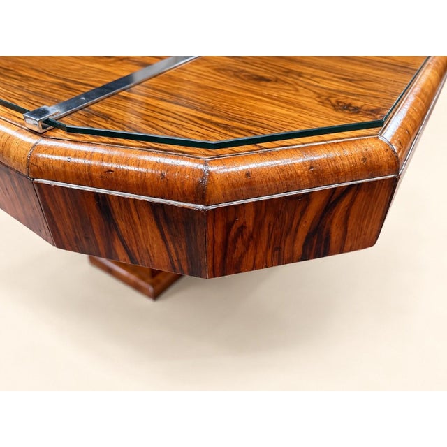 An Art Deco style extendable dining table with an octagonal top featuring chamfered corners, covered in a book-matched...