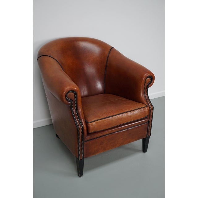 This cognac-colored leather club chair comes from the Netherlands. It is upholstered with cognac-colored leather and...