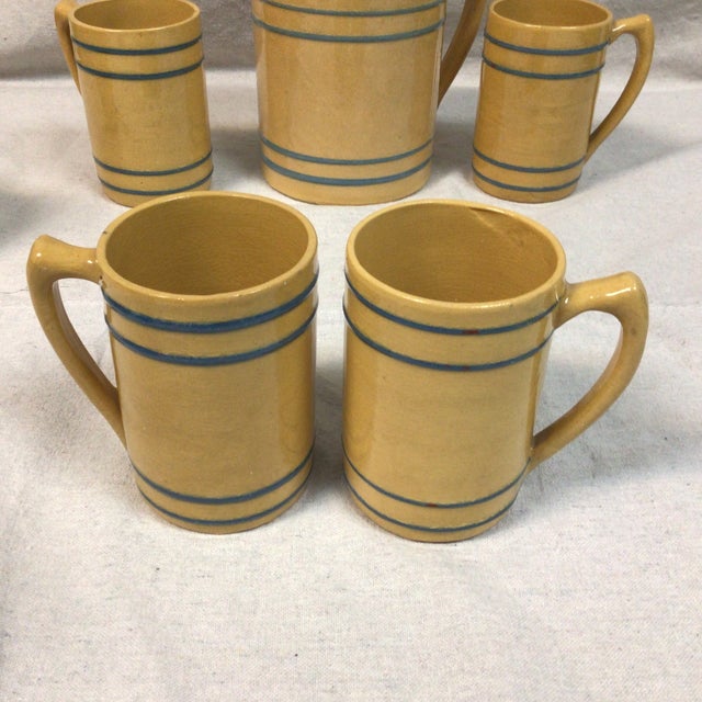 Set of Buckeye 1920’s/1930’’ yellow ware stoneware with the pitcher and 5 mugs. Root beer mugs. The mug’s measurements are...