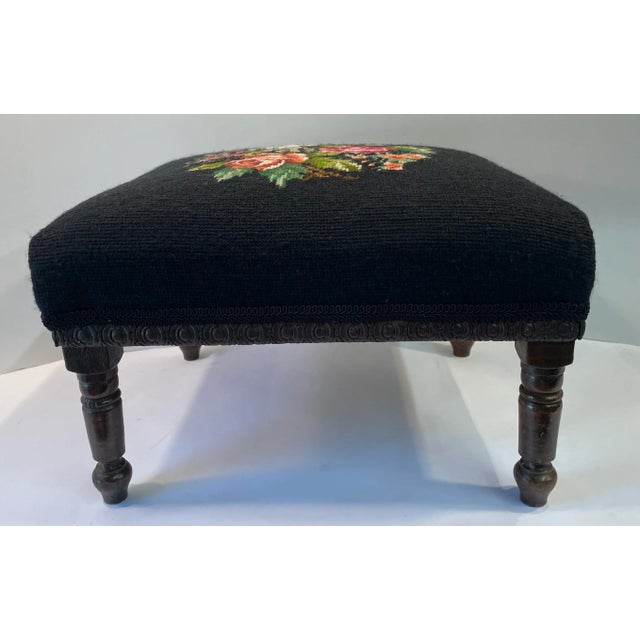 Beautiful black floral needlepoint footstool with a carved wooden base.