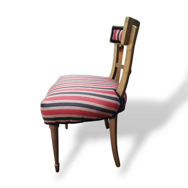 A charming pair of vintage neoclassical-style side chairs featuring elegantly tapered legs, curved back supports, and...