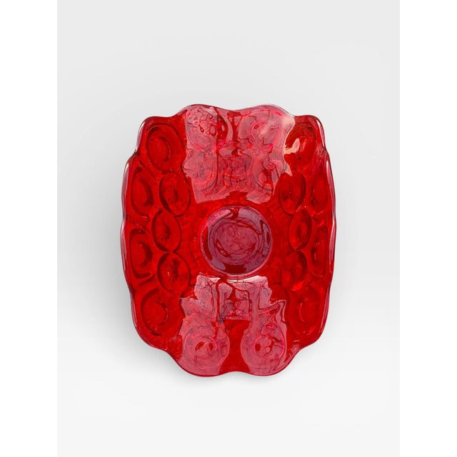 A striking vintage ruby red art glass pedestal bowl featuring a sculptural, undulating silhouette and deeply molded coin...