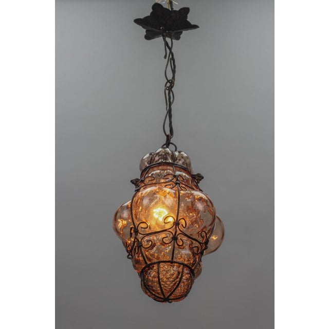 This beautiful Italian hanging lantern features clear amber smoke-colored Murano glass captivated within a metal frame....