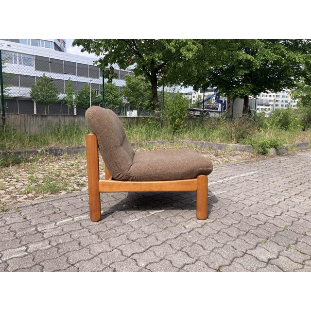 Mid-Century Vintage Easy Chair in Teak-Stained Beech Featuring a thick, durable brown wool upholstery. The chair combines...