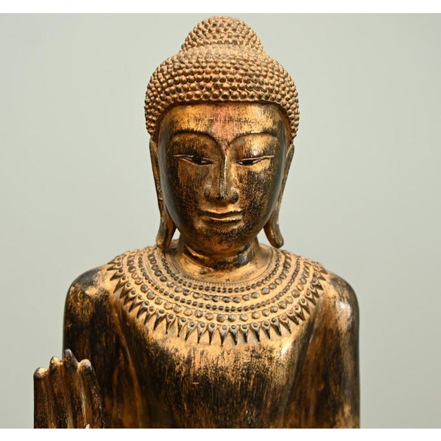 Impressive Burmese giltwood standing Buddha statue, circa 1950, finely carved and richly decorated in the traditional...