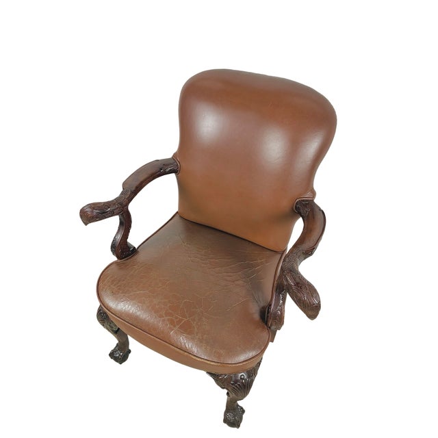 A striking vintage armchair by Maitland-Smith, combining warm brown leather upholstery with an elaborately carved dark-...