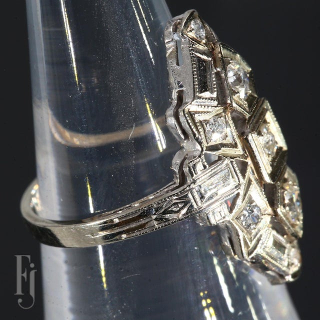 This is an Antique 14k White Gold Ring in an Art Deco Style. It features One Central Diamond, Two More Diamonds each...
