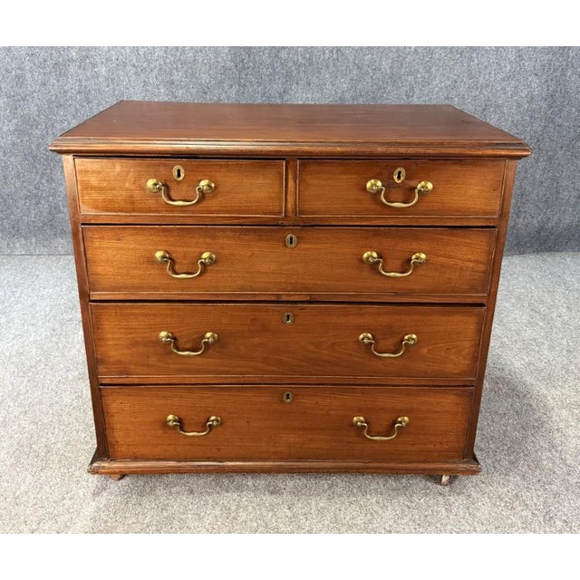 This 18th century solid mahogany chest features a classic five-drawer configuration with two over three drawers, warm aged...