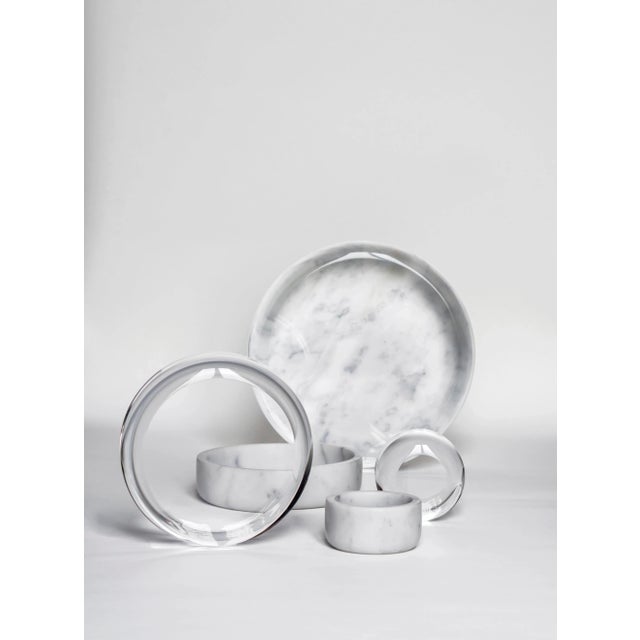 A collection of jewelry holders in white Carrara marble and transparent acrylic glass. The content is shown as submerged...