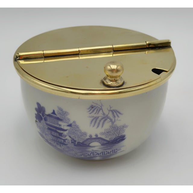 A charming vintage porcelain and polished brass covered sugar bowl featuring a blue-and-white Chinoiserie landscape motif...