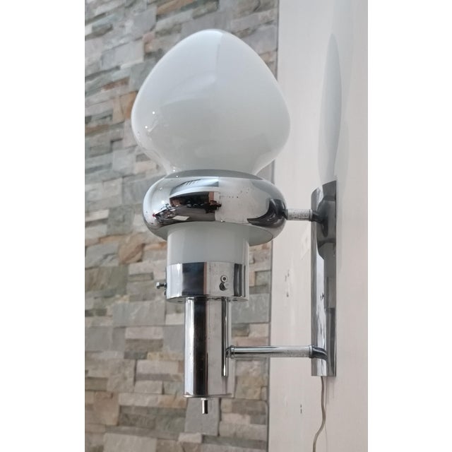Beautiful space-age wall sconce. Italy, 1970s. Chrome-plated metal frame. This piece is distinguished by its molded opal...