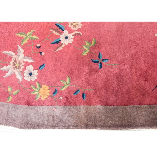 This vintage 1930s Chinese Art Deco rug features a vibrant red field with an elegant oval shape. The composition is...