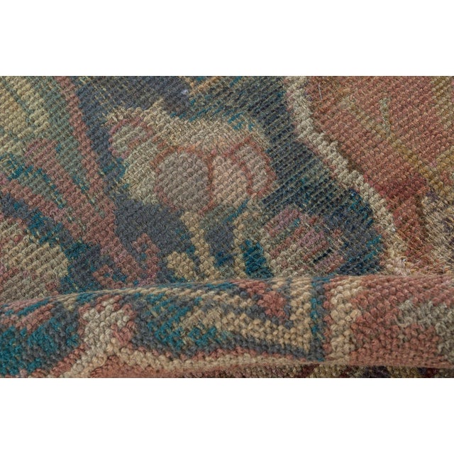 A narrow antique runner, the dusty rose field with stylized leaves and rosettes overall around a column of cusped...