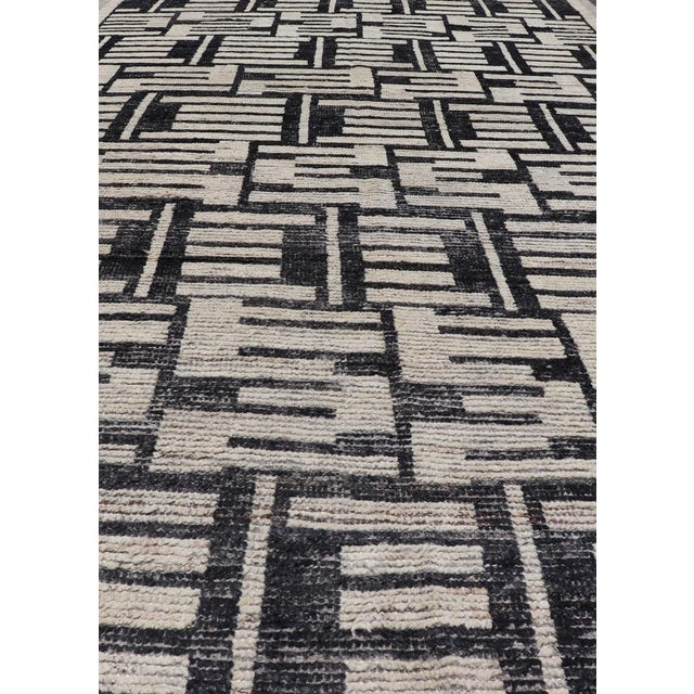 This Afghan hand-knotted area rug features an abstract, all-over design in ivory. The background is rich with ebony, while...