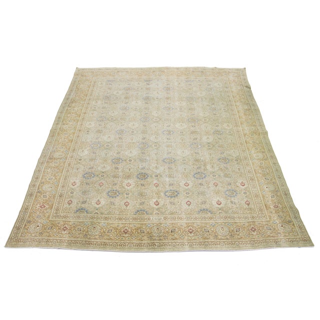 A Persian Tabriz wool rug from the 1920s showcases a handcrafted, traditional floral pattern. The design is accentuated by...