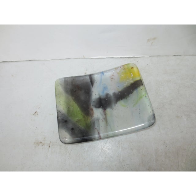 Thick heavy rectangular art glass slab curved over a bow form. The interior contains transparent color clouds of mauve and...