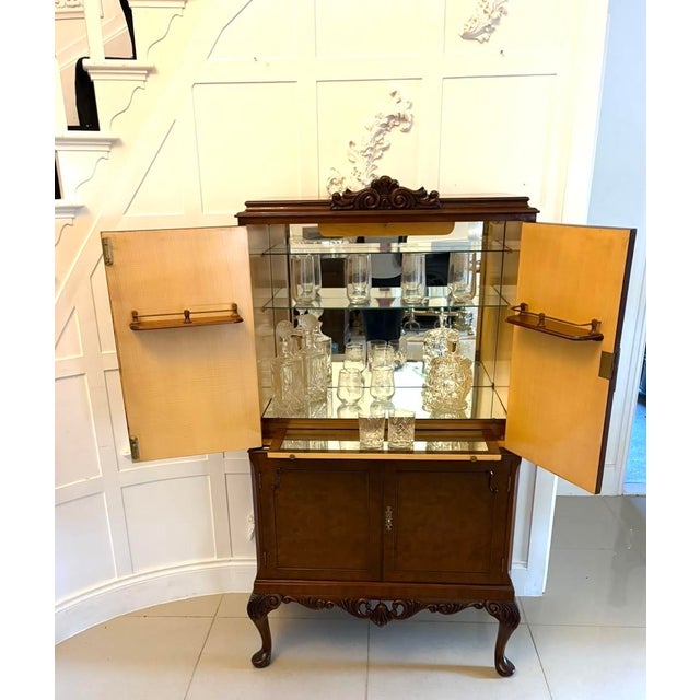 An antique burr walnut cocktail cabinet dating to the early 20th century, featuring beautifully figured burr walnut...