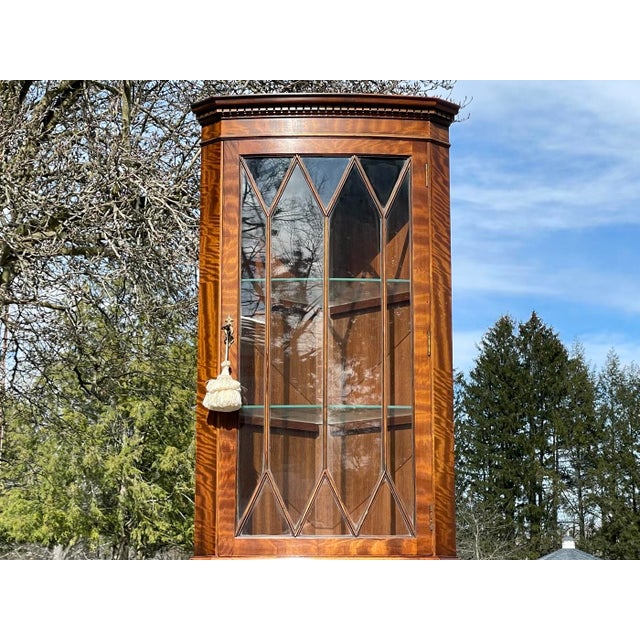 A vintage lighted mahogany English corner display cabinet with dentil moulded crown, divided glass, two glass shelves...