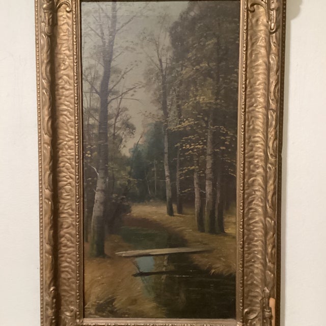 The product is an antique framed painting on canvas depicting a golden forest pass with a bridge over a stream. This...