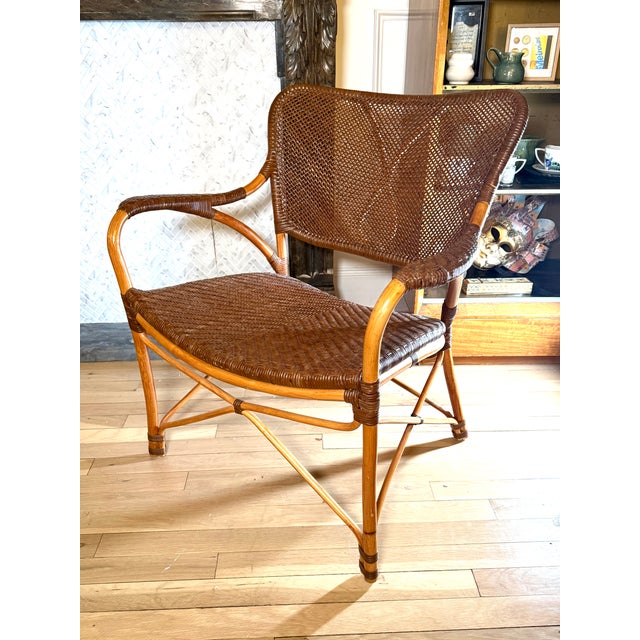 A stylish vintage 1950s rattan lounge chair featuring a gracefully curved frame and tightly hand-woven wicker seat and...