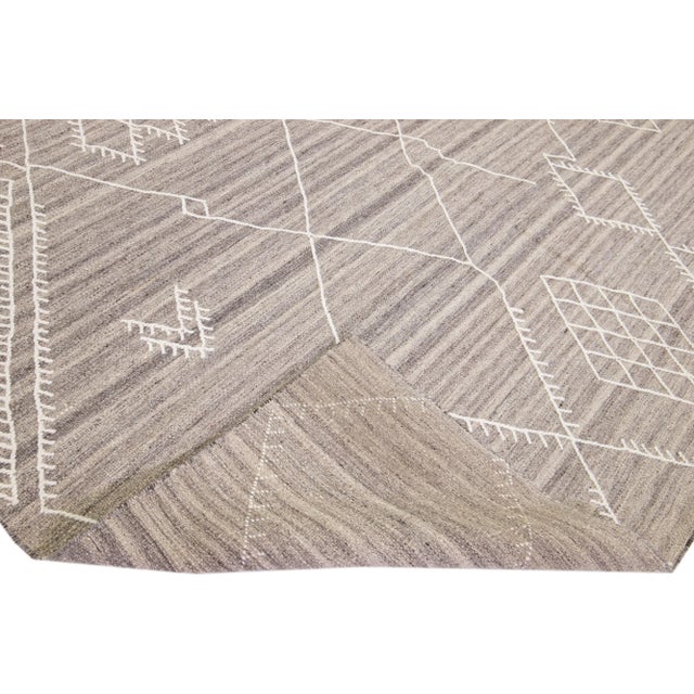 Beautiful kilim handmade wool rug with a beige-taupe color field. This custom modern flatweave rug of our Nantucket...