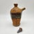 Hand-thrown stoneware pouring vessel with faceted body, speckled amber glaze, layered oxblood and teal banding, angled...