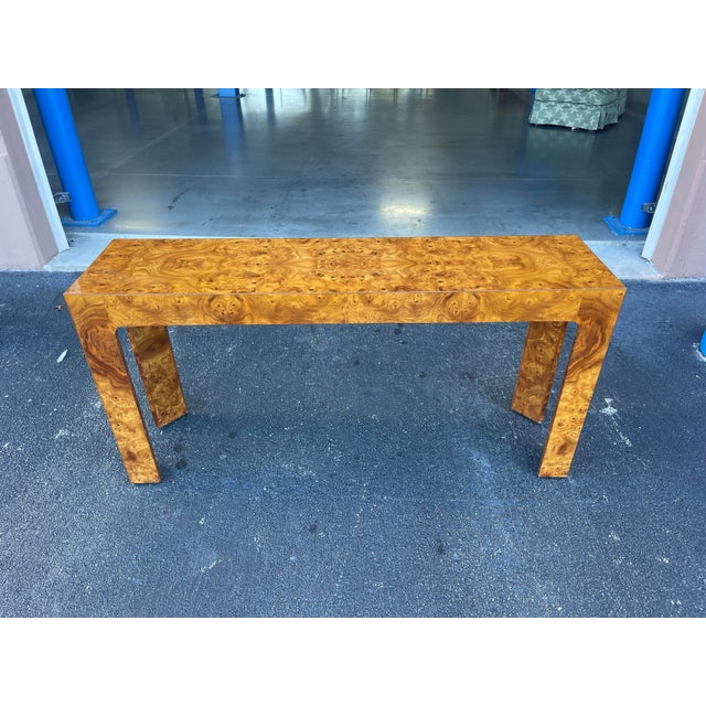 Striking vintage console table featuring richly figured burl wood veneer in a sleek waterfall silhouette. The elongated...