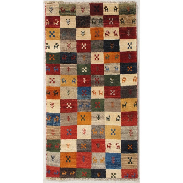 Hand-knotted Persian Gabbeh wool rug featuring a vibrant checkerboard field composed of multicolored squares with stylized...