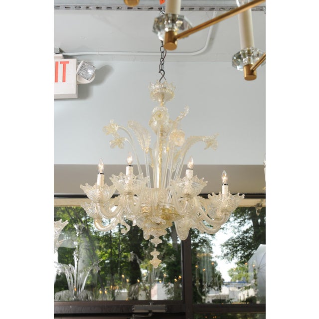 A striking Venetian chandelier composed of intricately worked glass leaves, flowers, and scrolling arms. Each of the eight...