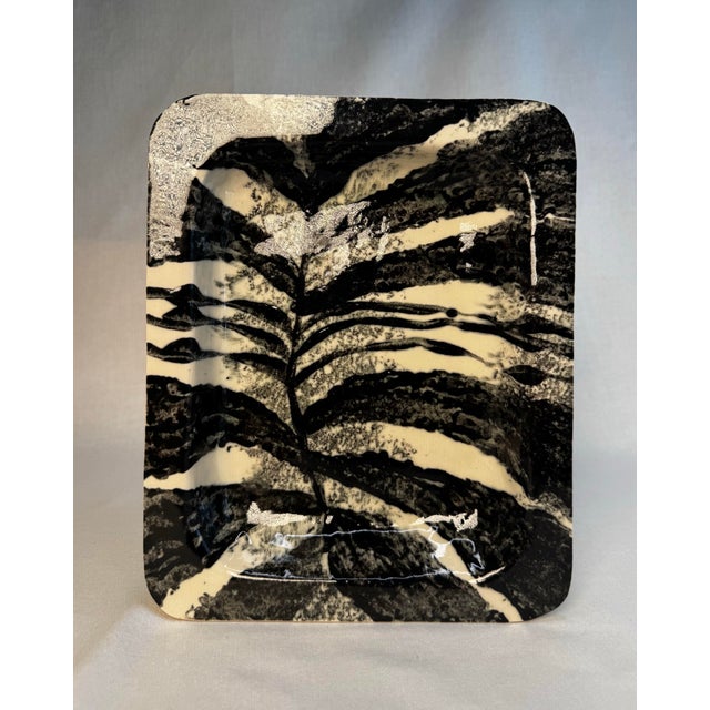 This shallow ceramic dish embodies a style often categorized as Graphic Organic Studio Art Pottery. It seamlessly merges...