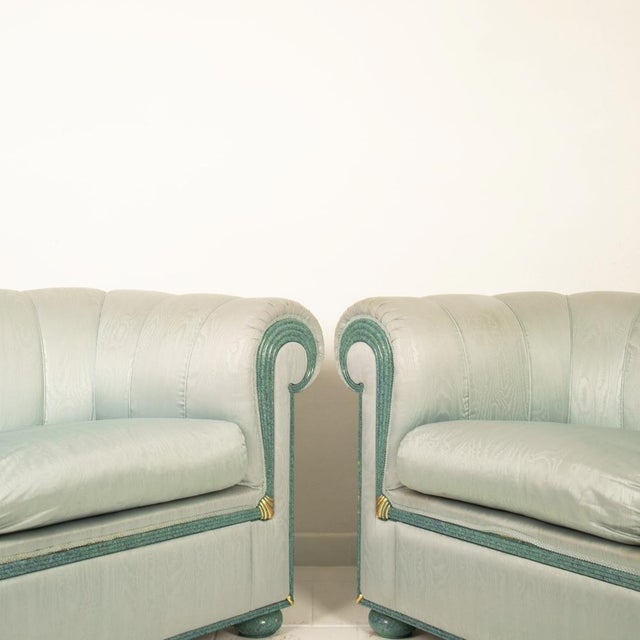 Elegante coppia di divani che si distinguono per la loro straordinaria rivestitura in seta moirè azzurra cangiante, che...