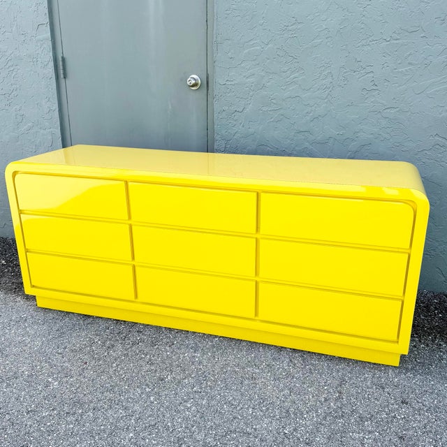This bold Postmodern waterfall dresser commands attention with its vibrant high-gloss yellow laminate finish and sleek,...