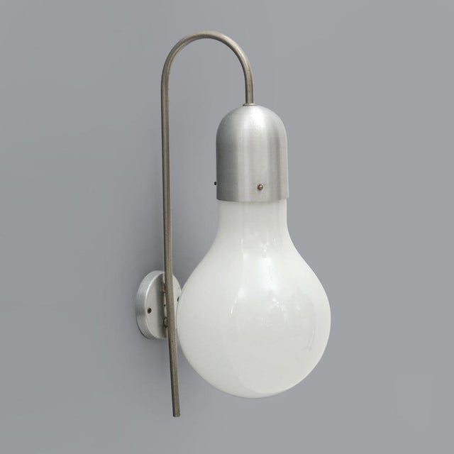 Wall lamp produced by Stilux Milano in the 1960s. Wall base and aluminum lamp body. Nickelated brass stem. White glass...