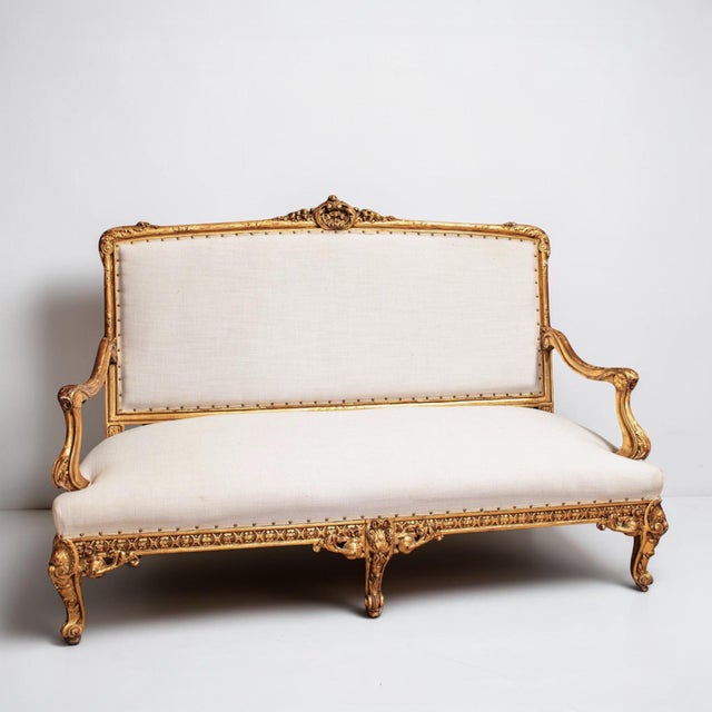 Elegant French Louis XVI giltwood settee with new linen upholstery, ribbon gimp, and nailhead trim. The body of the settee...