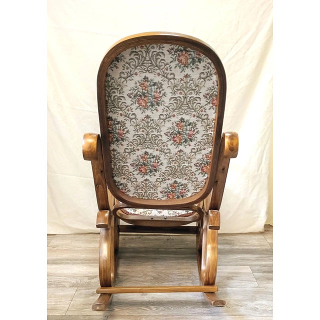 This vintage 1970s Victorian-Revival bentwood rocking chair features an ornate, sculptural triple-scroll frame in a warm...