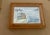 A charming original watercolor capturing a small boat resting on tranquil blue waters, with a seabird perched atop the...