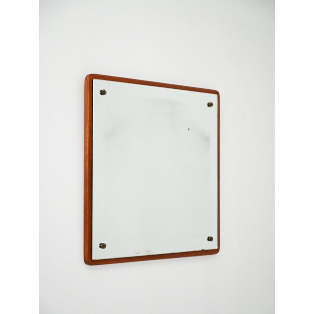 Square Scandinavian mirror with a thin teak frame and exposed metal screws at the corners. Scandinavian mirror from the...