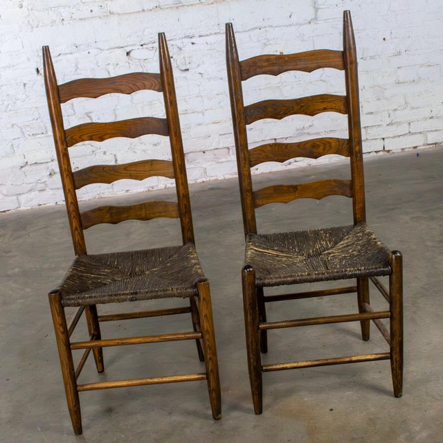 Fabulous vintage/antique French Country ladderback chairs composed of oak frames, serpentine or ogee carved slats, and...