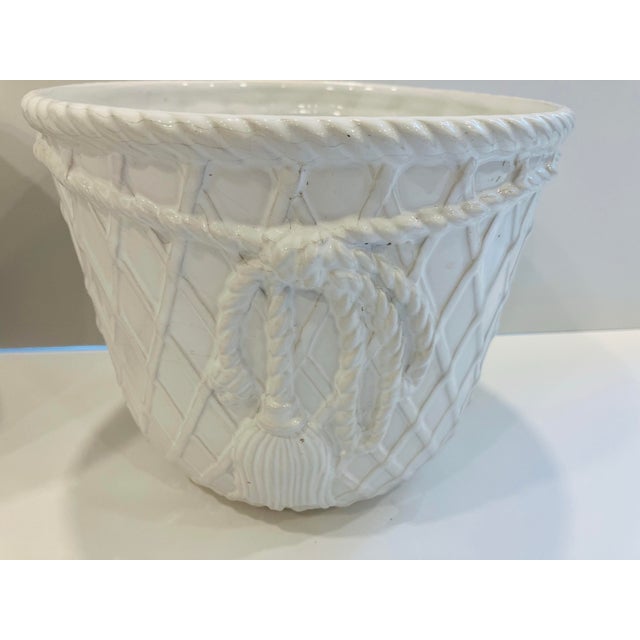This pair of ceramic jardineres have an all over trellis design with a rope and tassel accented on the front There is a...