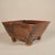 This handcrafted ceramic vessel features a square, tapered form elevated on four short, block-like feet. The vessel is...