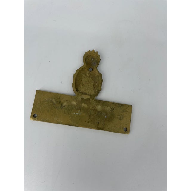 Small brass welcome plaque or sign with a pineapple.