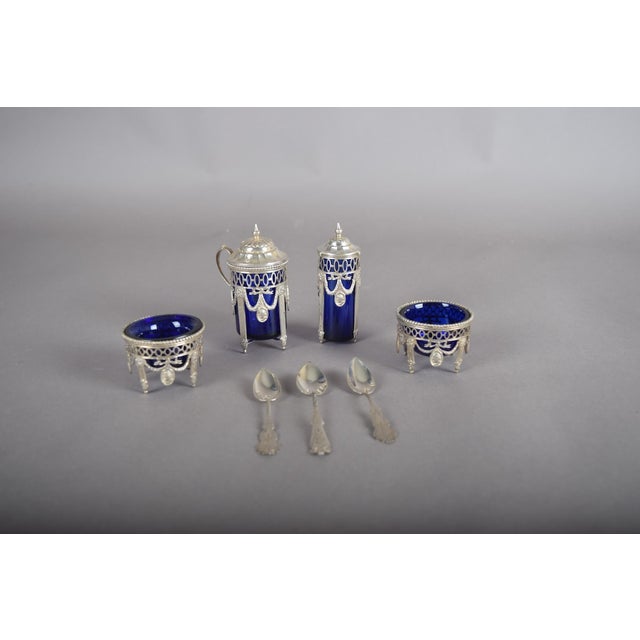 An exceptionally refined silver-mounted cobalt blue glass condiment set, comprising seven pieces in a cohesive Louis XVI...
