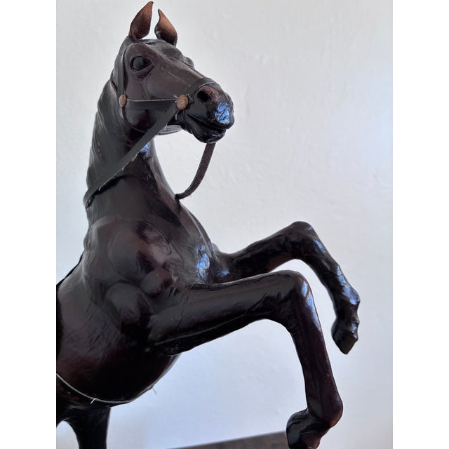 This leather horse statue is a handcrafted piece with detailed workmanship. It features a naturalistic form with glass...