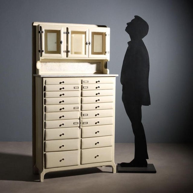 1950s laboratory cabinet. The cabinet features a double set of drawers that increase in size at the bottom, a marble top...