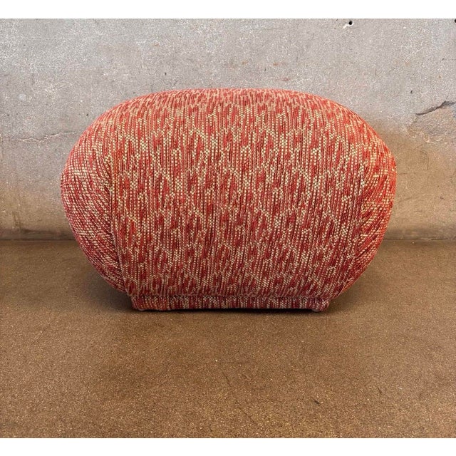 Sculptural vintage ottoman featuring a rounded silhouette and textured woven upholstery in warm rust, red, and cream...