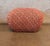 Sculptural vintage ottoman featuring a rounded silhouette and textured woven upholstery in warm rust, red, and cream...