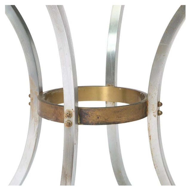 Maison Jansen style glass top center table featuring a sculptural silver metal base with gracefully curved saber legs, a...