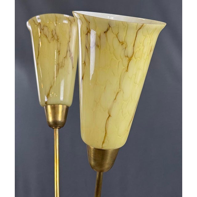 A charming three-arm floor lamp from the 1960s–70s featuring brass arched stems and yellow marbled glass shades. The round...
