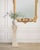 A sculptural hourglass-form pedestal stand painstakingly crafted out of tessellated stone with an elegant inset brass trim...